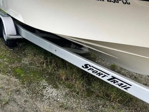 Slide: The Image of 2021 BlackJack 256 Coastal Bay boat on Sport Trail trailer, parked on grassy terrain. - 13