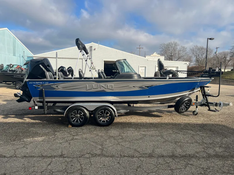 Slide: The Image of 2025 Lund 2075 IMPACT XS boat on trailer, parked outdoors under cloudy sky. - 8
