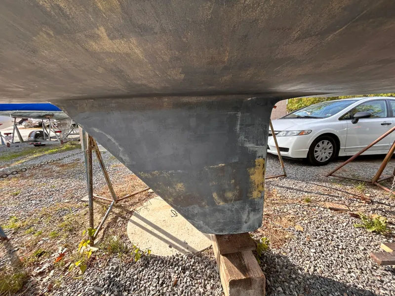 Slide: The Image of 1986 CAL 22 sailboat keel on gravel, with a car in the background. - 22