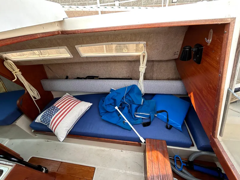 Slide: The Image of Interior of 1986 CAL 22 sailboat with blue cushions and American flag pillow. - 28
