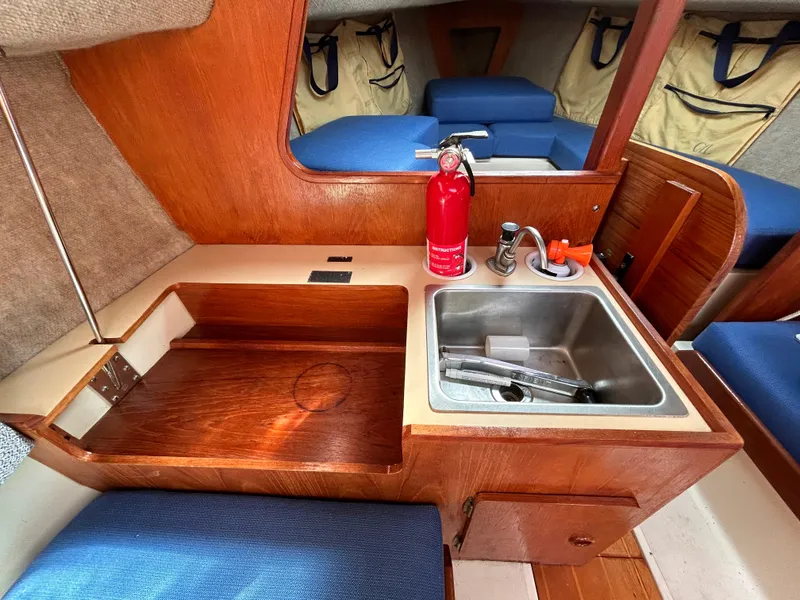 Slide: The Image of Compact boat kitchen with sink, fire extinguisher, and blue seating in CAL 22, 1986 model. - 29