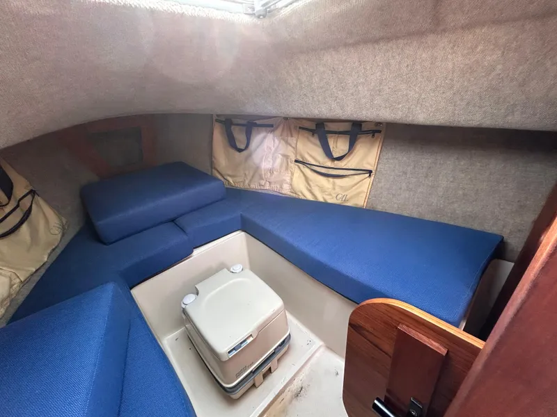 Slide: The Image of 1986 CAL 22 sailboat interior with blue cushions and portable toilet. - 33
