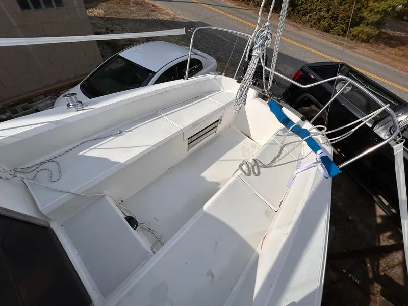 Slide: The Image of 1986 CAL 22 sailboat deck with ropes, parked near cars on a sunny day. - 4