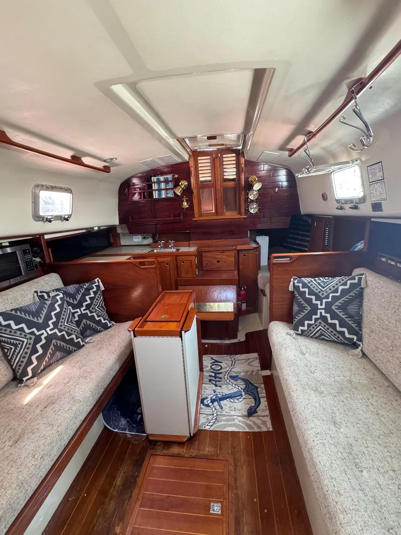 Slide: The Image of Interior of a 1985 Bayfield 32 sailboat with cozy seating and wooden finishes. - 18