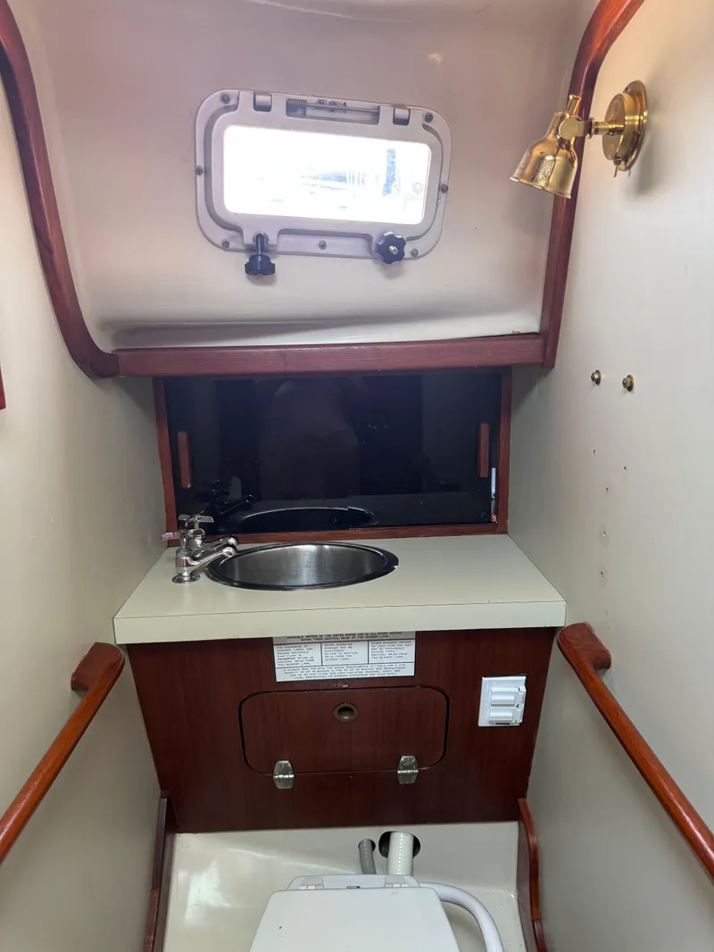 Slide: The Image of 1985 Bayfield 32 yacht interior with sink, porthole, and wooden accents. - 23