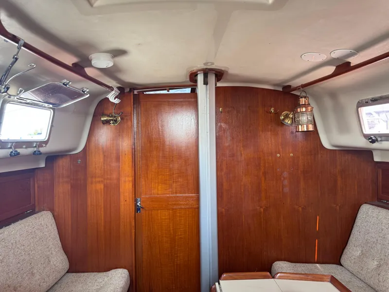 Slide: The Image of Interior of a 1985 Bayfield 32 sailboat with wooden paneling and cozy seating. - 25