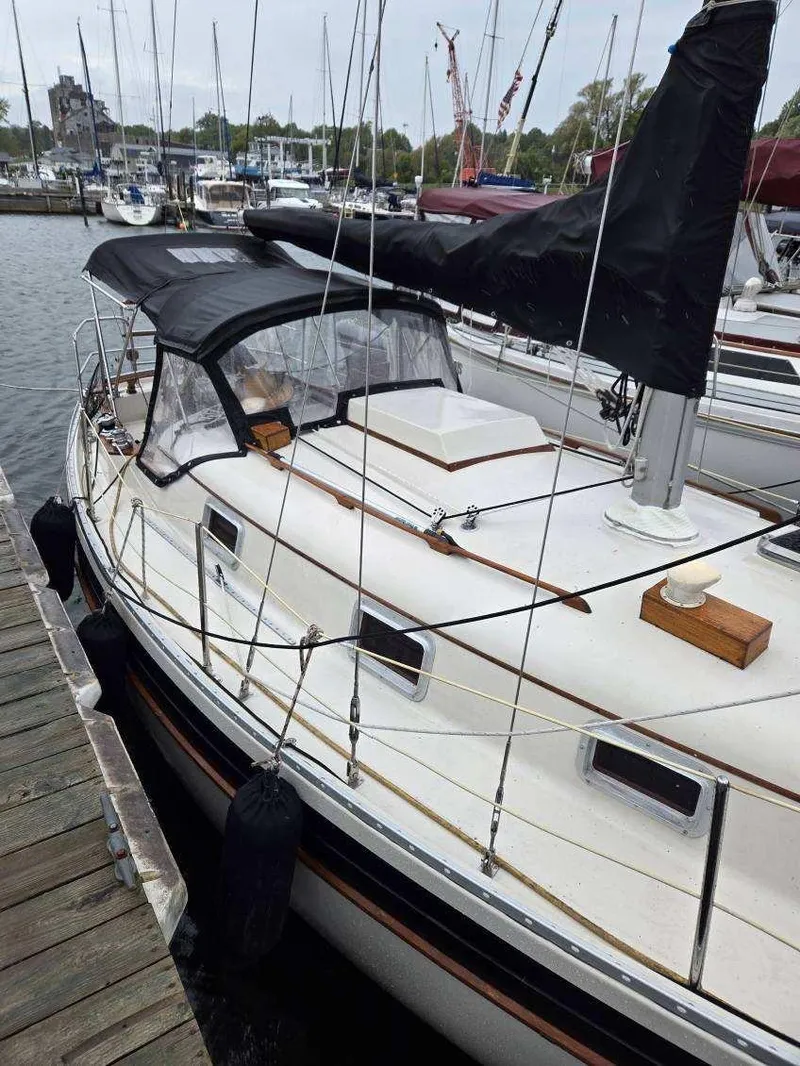 Slide: The Image of 1985 Bayfield 32 sailboat docked at a marina, featuring a black canopy and classic design. - 4