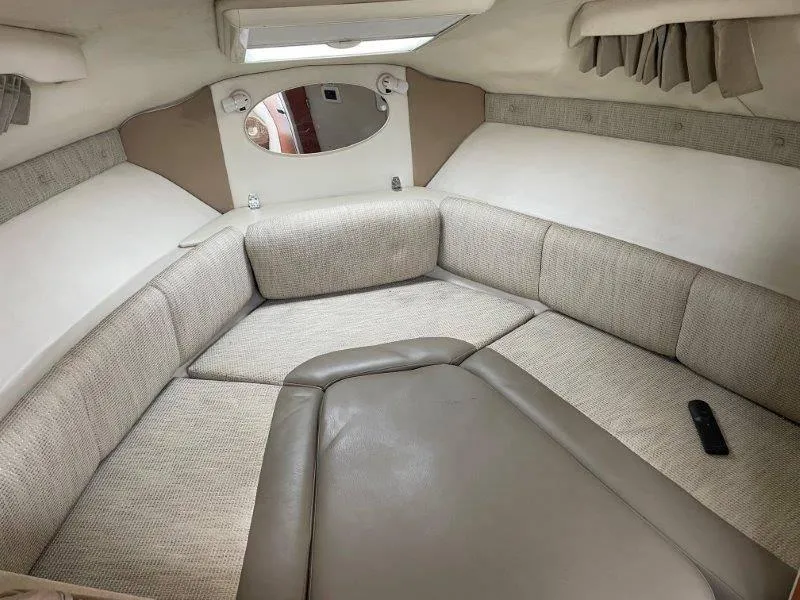 Slide: The Image of 2004 Chaparral 260 Signature cabin interior with beige seating and remote control. - 32