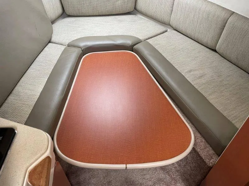 Slide: The Image of 2004 Chaparral 260 Signature cabin interior with cushioned seating and wooden table. - 34
