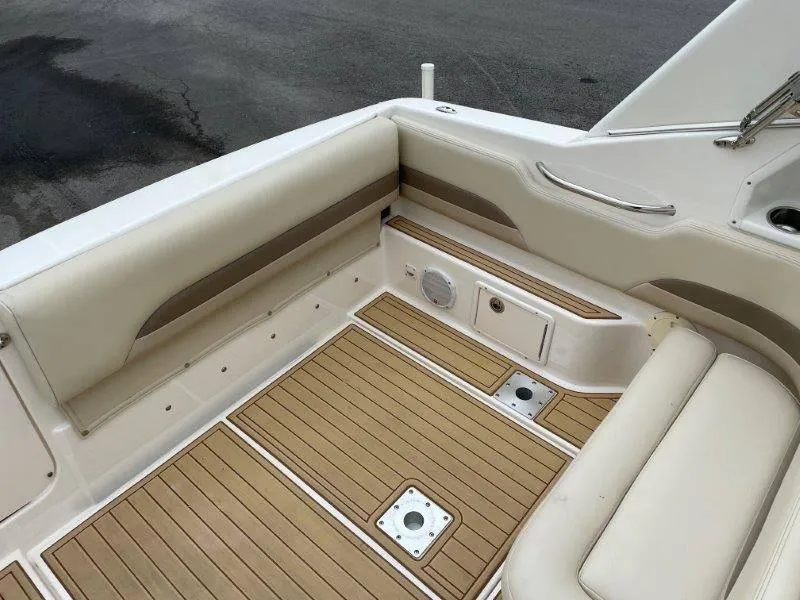 Slide: The Image of 2004 Chaparral 260 Signature boat interior with beige seating and wood flooring. - 43
