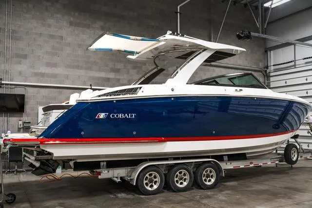 Slide: The Image of 2025 Cobalt R33 boat cruising on a tropical waterway with palm trees in the background. - 1