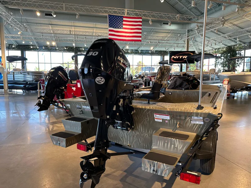 Slide: The Image of 2025 Tracker Grizzly 1654 T Sportsman boat in showroom with American flag. - 2