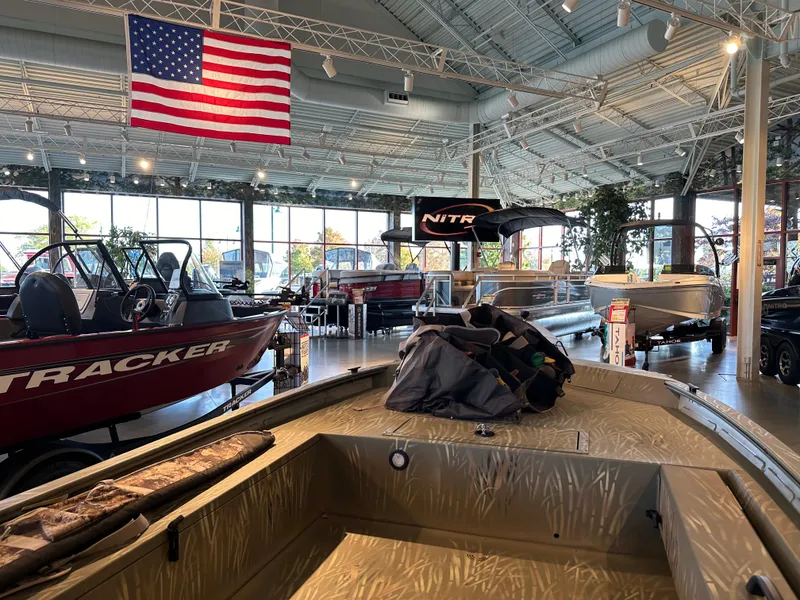 Slide: The Image of 2025 Tracker Grizzly 1654 T Sportsman boat in showroom with American flag. - 5