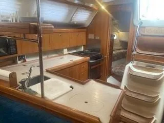 Slide: The Image of Interior of 2003 Hunter 386 sailboat with kitchen and stairs, featuring wood cabinetry. - 34