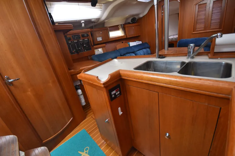 Slide: The Image of Interior of a 2003 Hunter 386 sailboat featuring a wooden kitchen and dual sink. - 44
