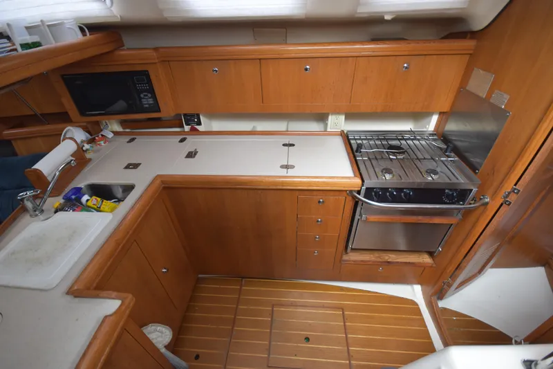 Slide: The Image of 2003 Hunter 386 yacht kitchen with wooden cabinetry and compact appliances. - 32