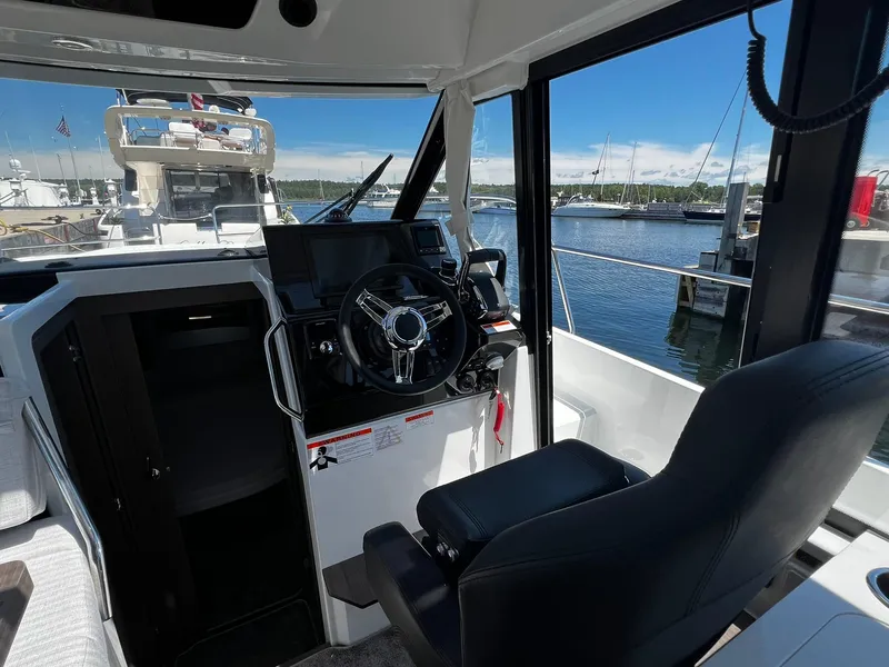 Slide: The Image of 2025 Jeanneau NC 895 helm with steering wheel, dashboard, and marina view. - 15