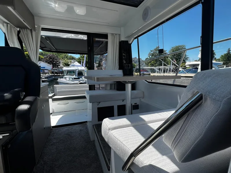 Slide: The Image of Interior of 2025 Jeanneau NC 895 boat, featuring seating and table with marina view. - 19