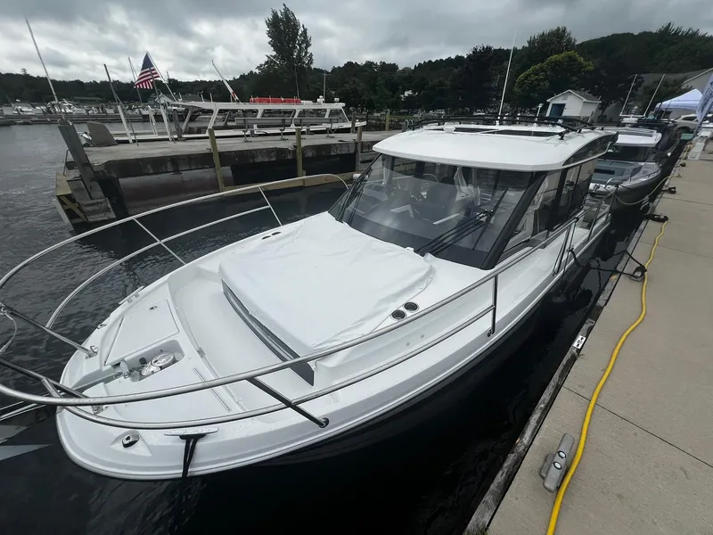 Slide: The Image of 2025 Jeanneau NC 895 docked at a marina under cloudy skies. - 2