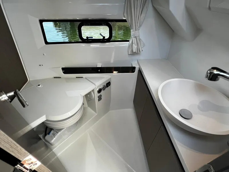 Slide: The Image of 2025 Jeanneau NC 895 boat bathroom with modern sink, toilet, and window view. - 21