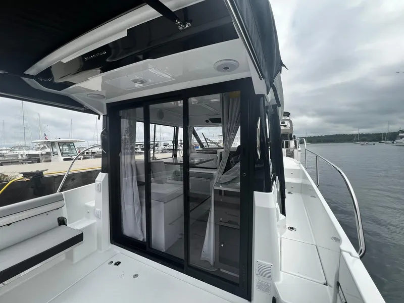 Slide: The Image of 2025 Jeanneau NC 895 boat with sliding glass doors, docked at a marina. - 5