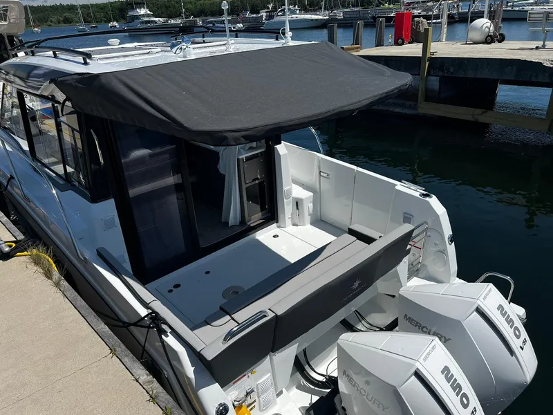 Slide: The Image of 2025 Jeanneau NC 895 boat docked, featuring dual Mercury outboard engines and a shaded deck area. - 6