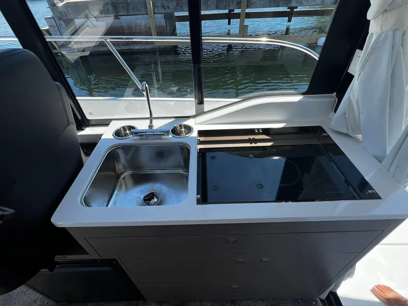 Slide: The Image of Compact kitchen area on 2025 Jeanneau NC 895 boat with sink and stove. - 9