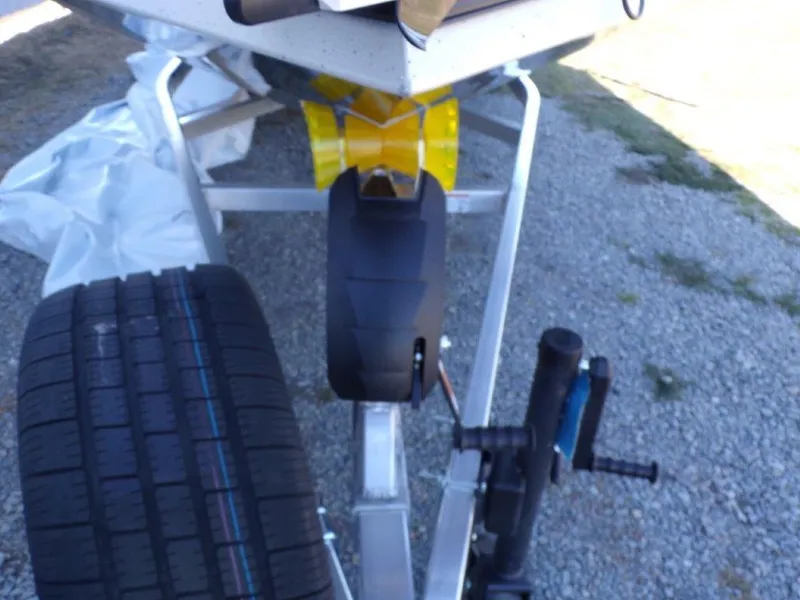Slide: The Image of Trailer hitch and wheel assembly of 2025 Xpress H24Bay boat on gravel surface. - 21