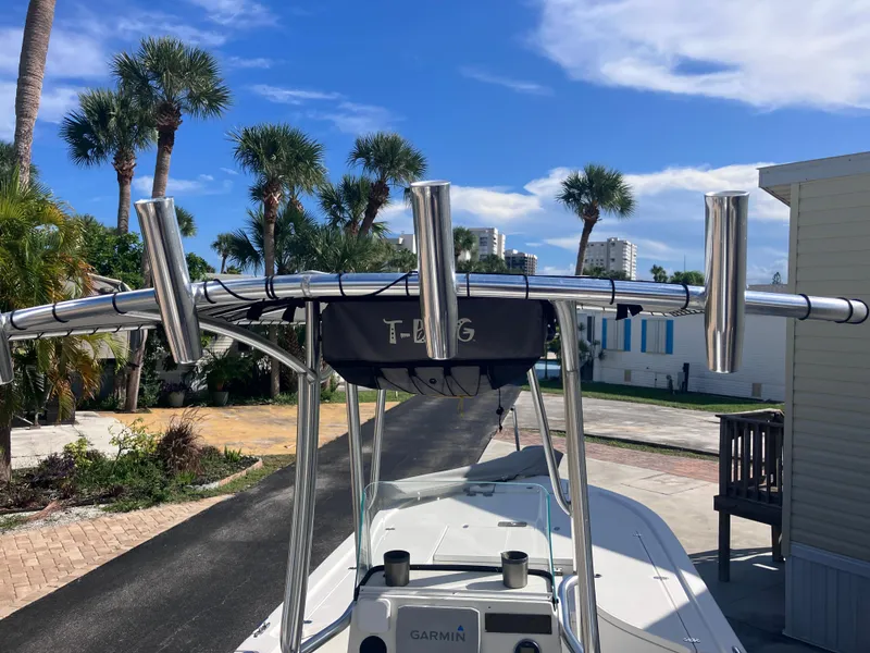 Slide: The Image of 2015 Sea Born FX24 Bay boat with T-top and rod holders, parked near palm trees. - 13