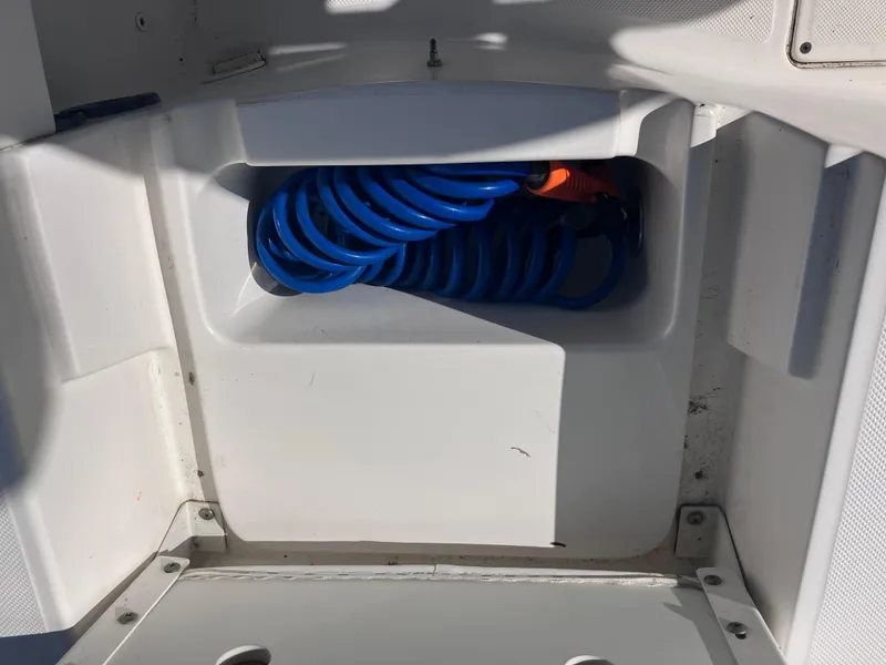 Slide: The Image of Storage compartment with blue coiled hose in 2015 Sea Born FX24 Bay boat. - 22