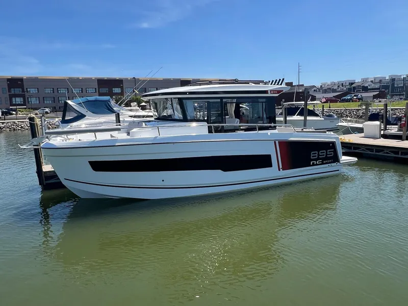 Slide: The Image of 2025 Jeanneau NC 895 Sport S2 boat docked in marina under clear blue sky. - 2