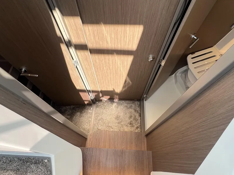 Slide: The Image of Interior of 2025 Jeanneau NC 895 Sport S2, featuring wooden steps and compact bathroom. - 23