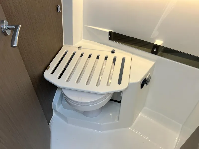Slide: The Image of 2025 Jeanneau NC 895 Sport S2 bathroom with compact toilet and foldable cover. - 26