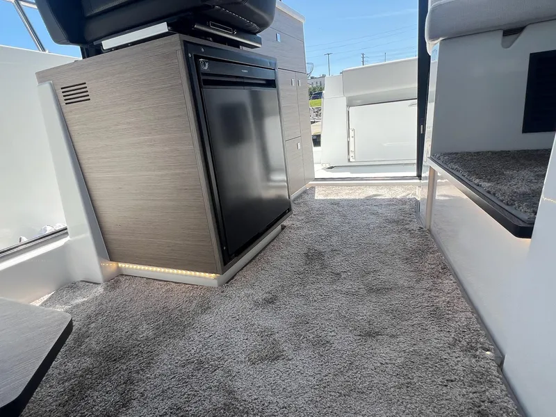 Slide: The Image of Interior of 2025 Jeanneau NC 895 Sport S2 boat, featuring carpeted flooring and compact refrigerator. - 38