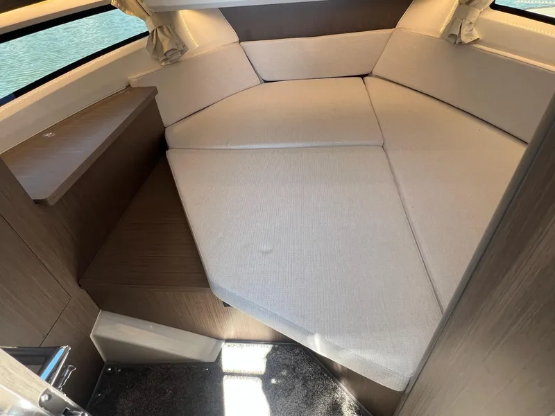 Slide: The Image of 2025 Jeanneau NC 895 Sport S2 cabin interior with beige cushions and wooden accents. - 42