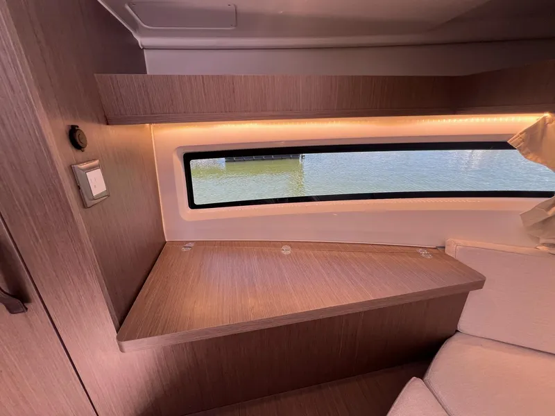 Slide: The Image of Interior of 2025 Jeanneau NC 895 Sport S2 with wood finish and window view. - 48