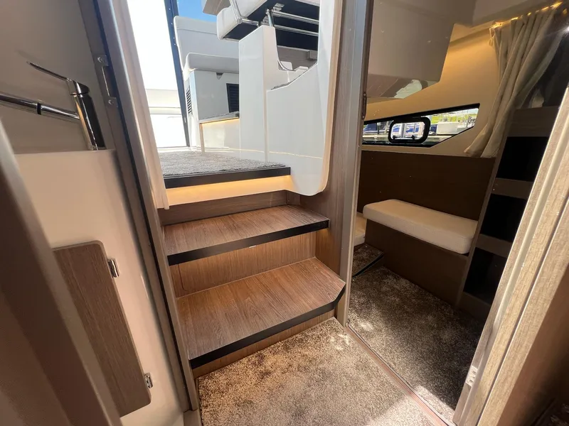 Slide: The Image of Interior view of 2025 Jeanneau NC 895 Sport S2, featuring wooden steps and cozy cabin space. - 49