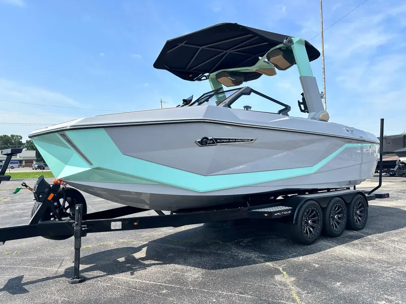 Slide: The Image of 2025 Nautique G23 boat with teal accents on a trailer, under a clear blue sky. - 11