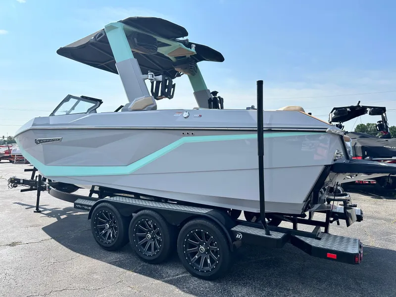 Slide: The Image of 2025 Nautique G23 boat on trailer, sleek design, light blue accents, sunny day. - 12