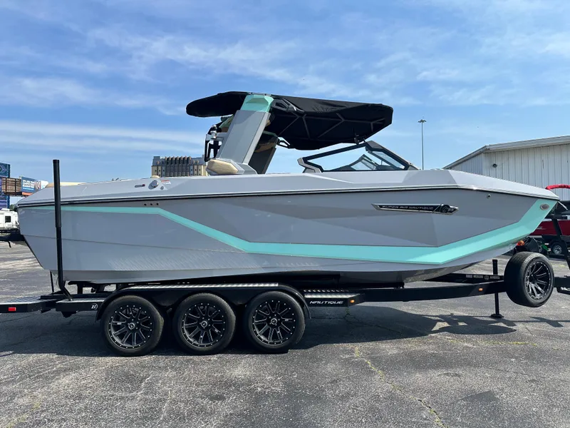 Slide: The Image of 2025 Nautique G23 boat on trailer, gray with teal accents, parked outdoors. - 4