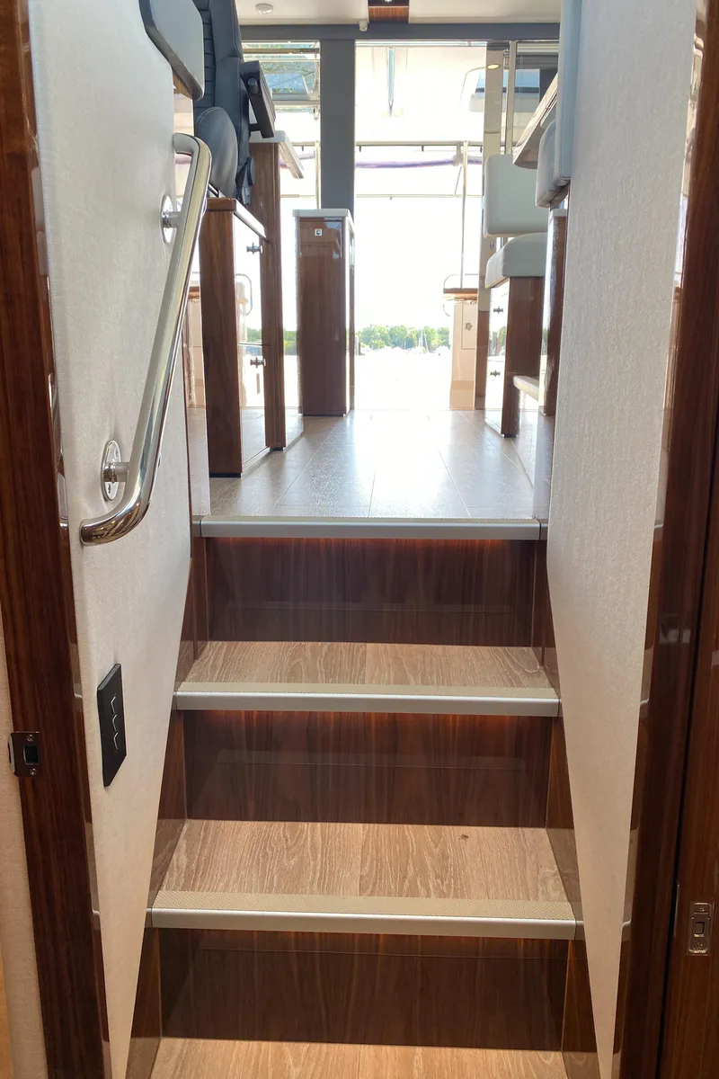 Slide: The Image of Staircase inside 2025 Riviera 465 SUV yacht, featuring sleek wooden design. - 36