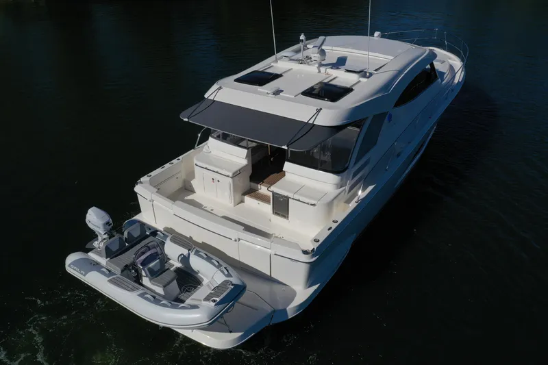 Slide: The Image of 2025 Riviera 465 SUV luxury yacht with attached dinghy on calm water. - 9