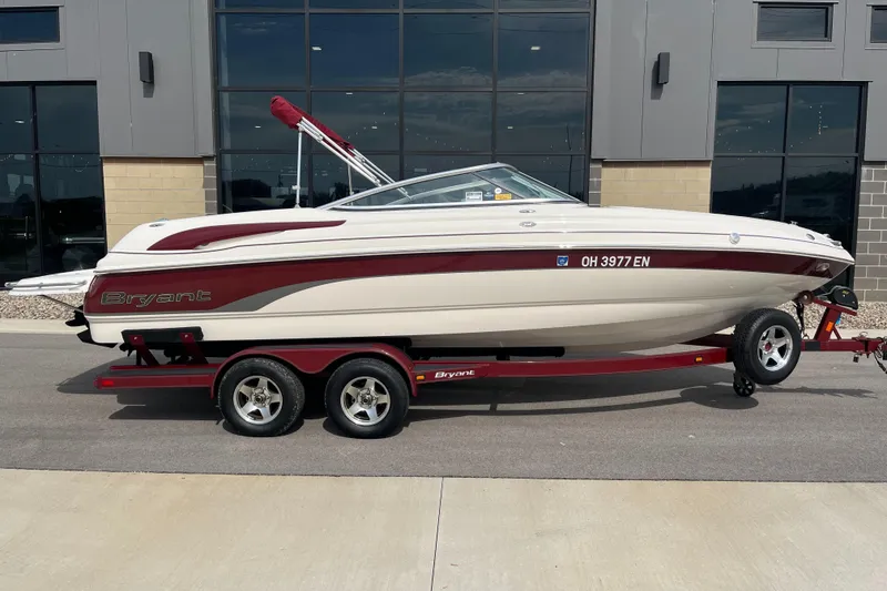 Slide: The Image of 2008 Bryant 239 boat on trailer, parked outside a modern building. - 2