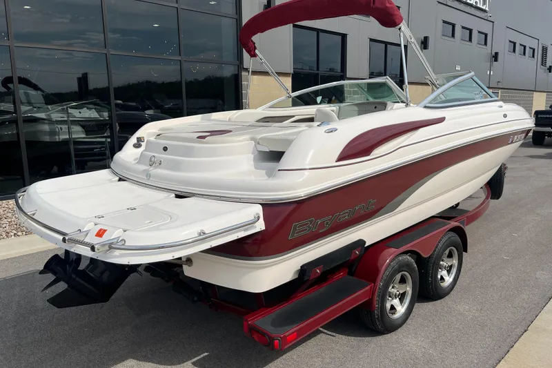 Slide: The Image of 2008 Bryant 239 boat with red accents on a trailer, parked outside a showroom. - 3