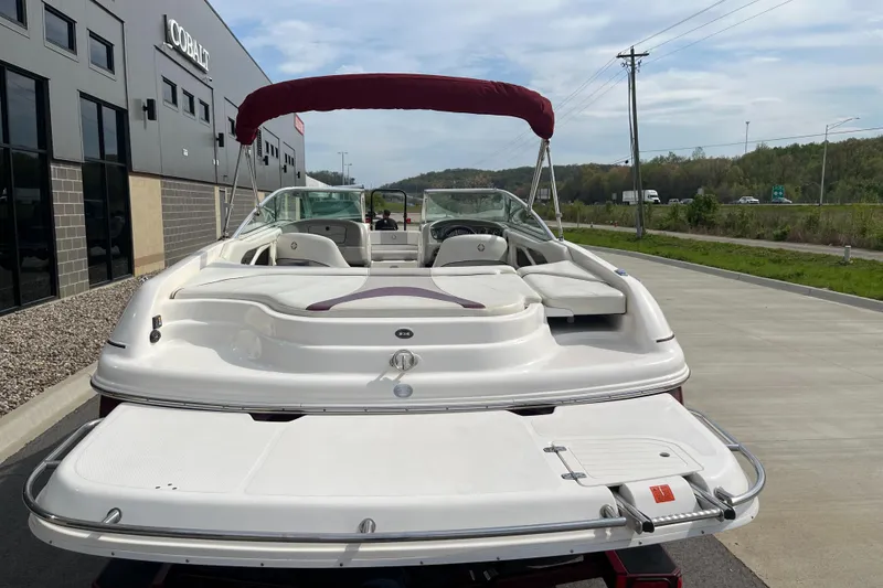 Slide: The Image of 2008 Bryant 239 boat with red canopy, parked near a modern building. - 7