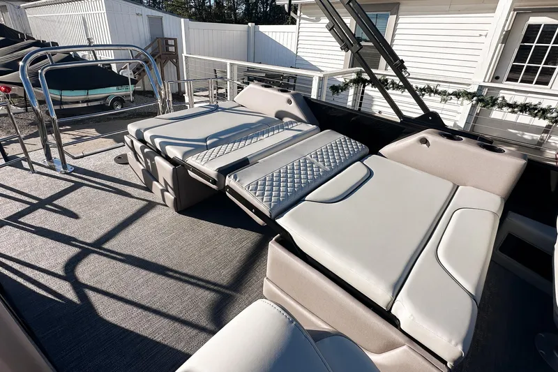 Slide: The Image of 2025 Godfrey Sweetwater 24' Tritoon interior with drop table lounge, showcased at a boat exhibition. - 12