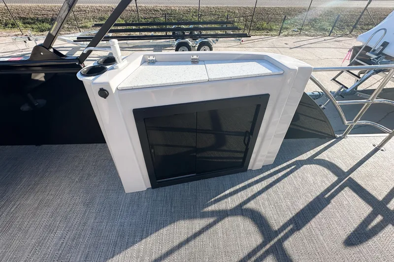 Slide: The Image of 2025 Godfrey Sweetwater 24' Tritoon with drop table lounge seating, showcased indoors. - 14