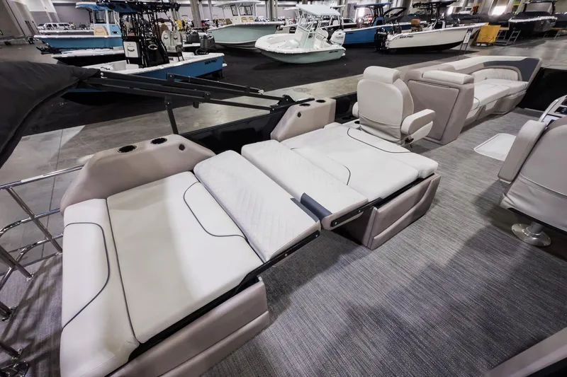 Slide: The Image of 2025 Godfrey Sweetwater 24' Tritoon with drop table lounge seating, showcased indoors. - 17