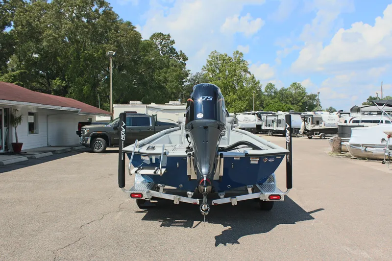 Slide: The Image of 2025 Avid 23 FSX boat with motor, parked in a lot with RVs and trees. - 9