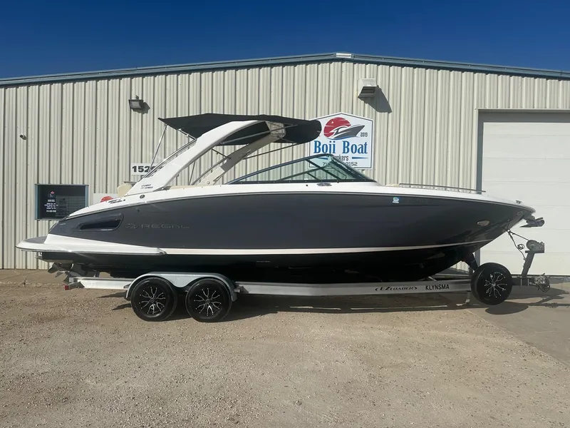 Slide: The Image of 2023 Regal 2800 boat on trailer outside a building under clear blue sky. - 0